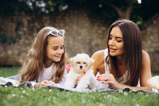 Photo mother with daughter together with dog maltipa in the back yard