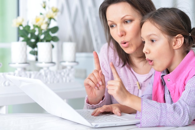 Mother with daughter using laptop