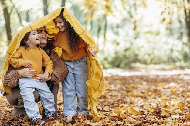 Mother with daughters having fun in autumnal park