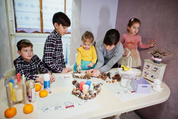 Mother with four kids makes a wreath for Christmas Eve and crafting decorating. New Year celebration.