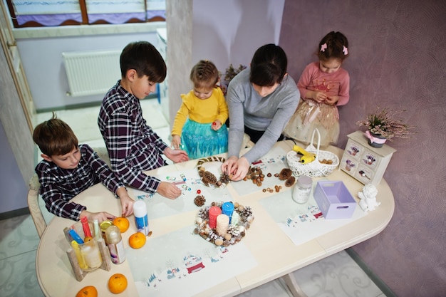 Mother with four kids makes a wreath for Christmas Eve and crafting decorating. New Year celebration.