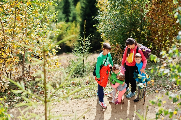 Mother with four kids in mountains. Family travel and hiking with childrens. Sisters is hug each other.