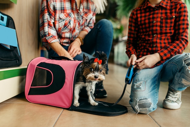 Madre con la ragazza che sceglie la borsa per il piccolo cucciolo nel negozio di animali.