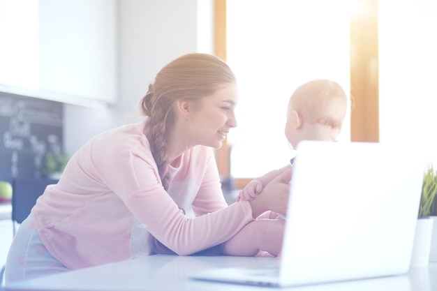 Mother with her baby in the bright kitchen at home