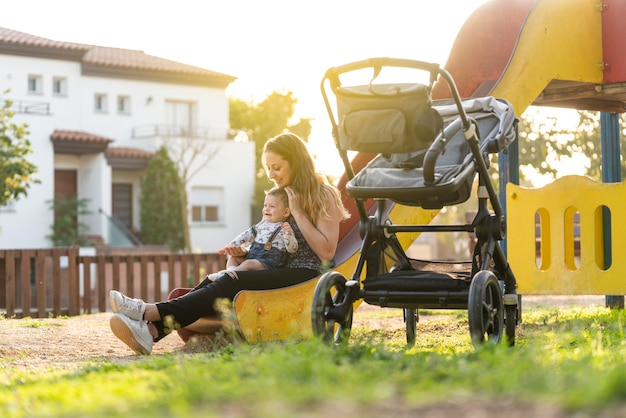 Mother with her baby on a park slide as the sun sets