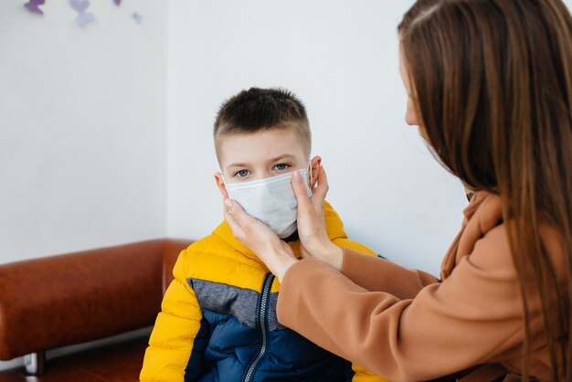 隔離中、子供を持つ母親が仮面に立っています。パンデミック、コロナウイルス