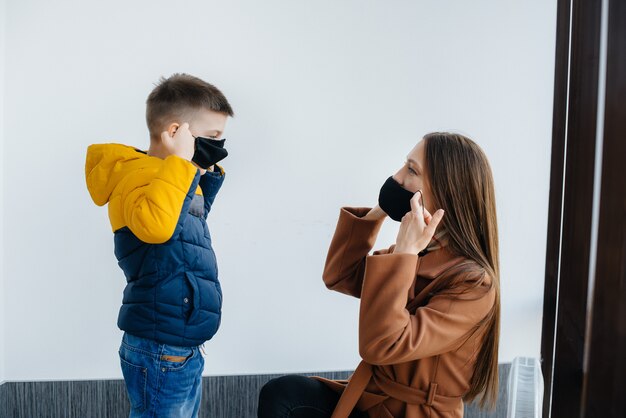 検疫中に子供を持つ母親がマスクに立っている