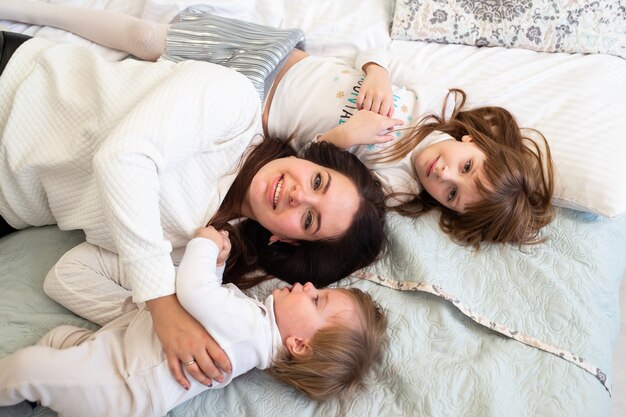 Mother with her children boy and girl on bed