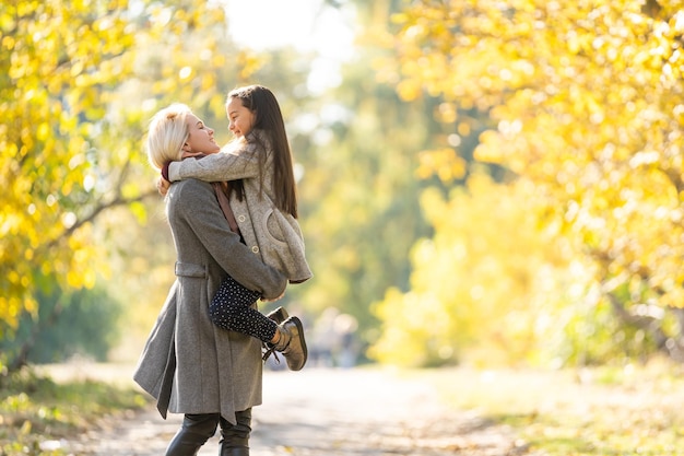 mother with her daughter in autumnal alley.