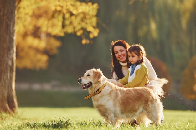 Mother with her daughter have walk with Golden Retriever dog in the park