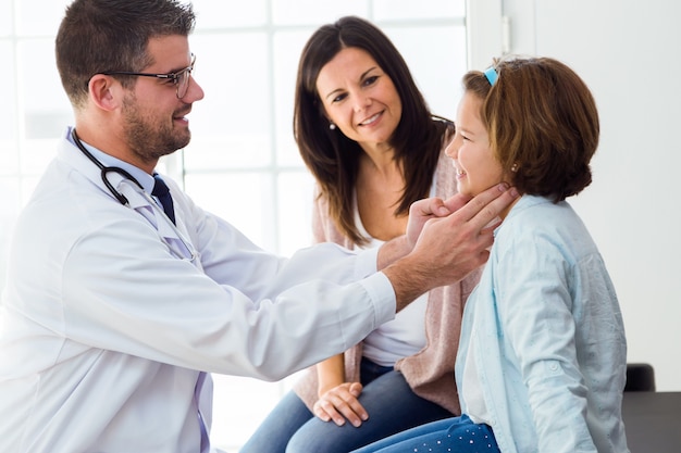 Mother with her daughter having throat examination by pediatrician in the office.