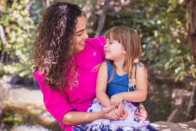 Mother with her daughter in her lap in the park. Beautiful young mother with her daughter in the park. Mothers Day