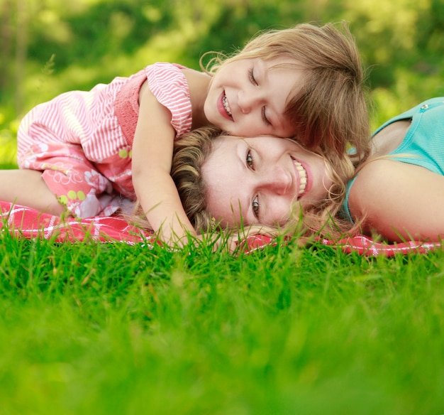 Mother with her happy  little daughter lie on the grass