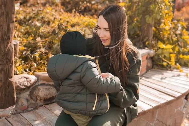 Photo mother with her little asian son in autumn park woman zips up child jacket fall and motherhood