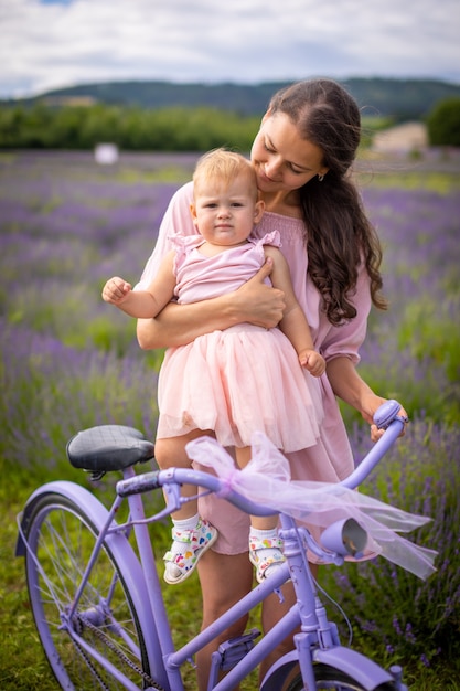 Mother with her little daugher on purple bicycle on lavender background in Czech republic