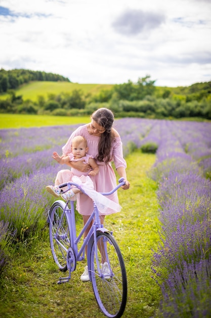 Mother with her little daugher on purple bicycle on lavender background czech republic