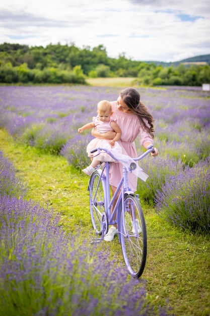 ラベンダーの背景チェコ共和国の紫色の自転車に彼女の小さな娘を持つ母