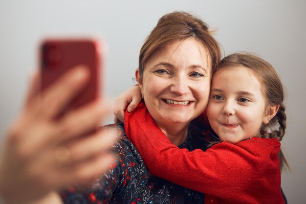 Photo mother with her little daughter making video call using mobile phone keeping distance