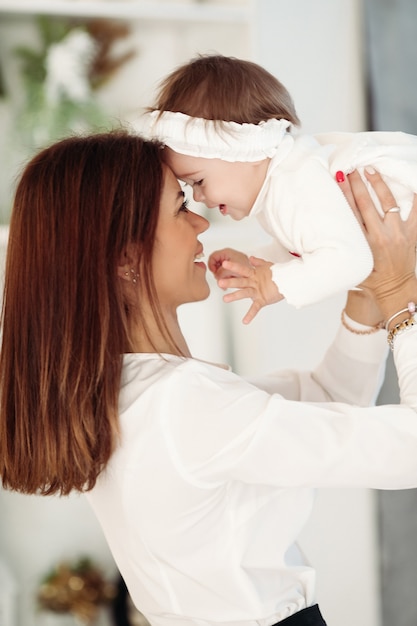 Mother with her little daughter near the Christmas tree at home