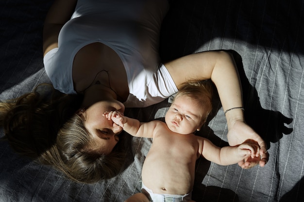 写真 彼女の生まれたばかりの息子を持つ母は日光の光線でベッドに横たわっていた