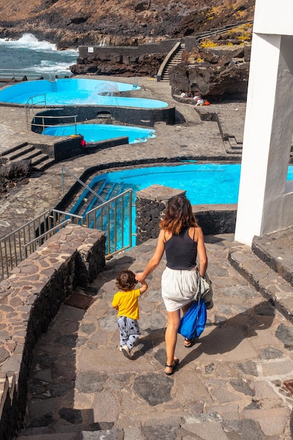 El Hierro Canary Islands의 바다 옆 La Caleta 마을 수영장에 아들과 함께 도착한 어머니