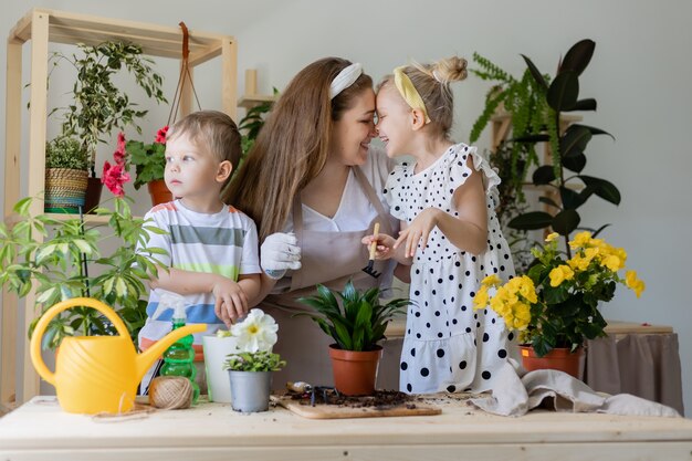 Mother with her son and daughter in fasting plant or transplant indoor flowers lifestyle