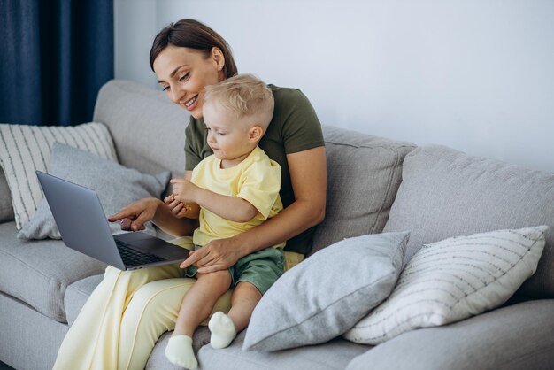 Mother with her son sitting on sofa and using laptop