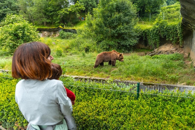 A mother with her son visiting a brown bear in a park in the municipality of Borce in the French Pyrenees