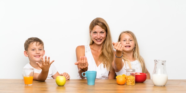Mother with her two children having breakfast doing coming gesture