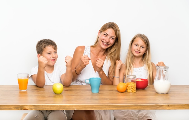 Mother with her two children having breakfast and making victory gesture
