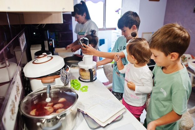 キッチンで料理をしている子供を持つ母親幸せな子供の瞬間