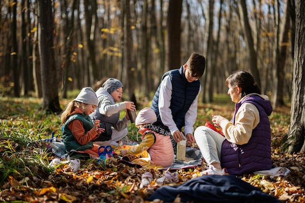 秋の森で家族でピクニックする子供を持つ母親