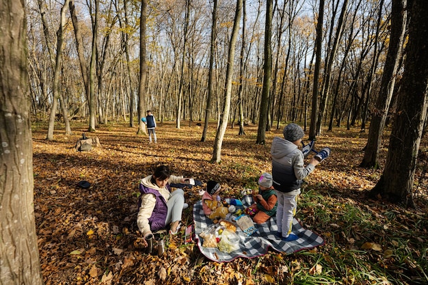 秋の森で家族でピクニックする子供を持つ母親