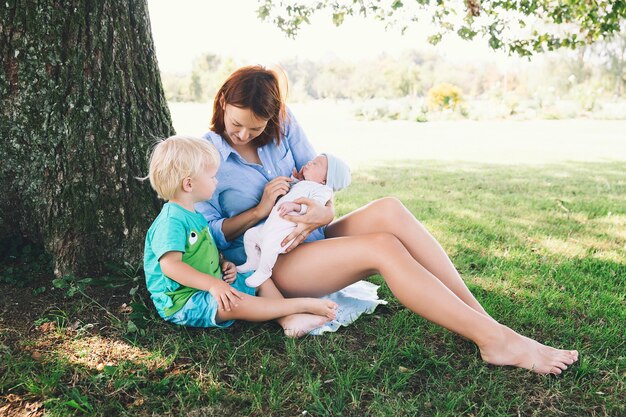 Mother with little baby daughter and older son on walking outdoor