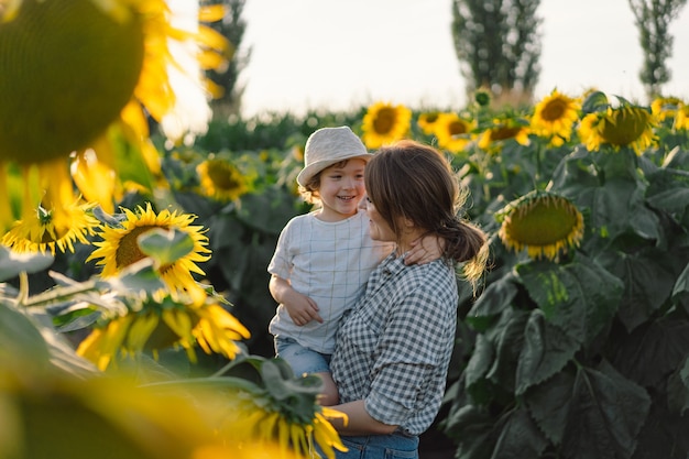 Premium Photo | Mother with little baby son in sunflowers field during ...