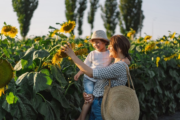 Mother with little baby son in sunflowers field during golden hour mom and son are active in nature