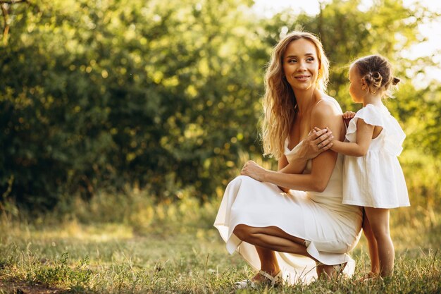 Madre con la piccola figlia in bei vestiti che camminano nella foresta