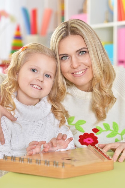 Mother with little daughter playing on instrumen