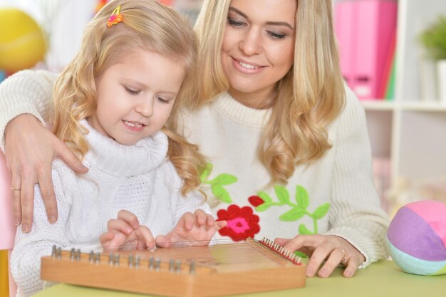 Mother with little daughter playing on instrumen