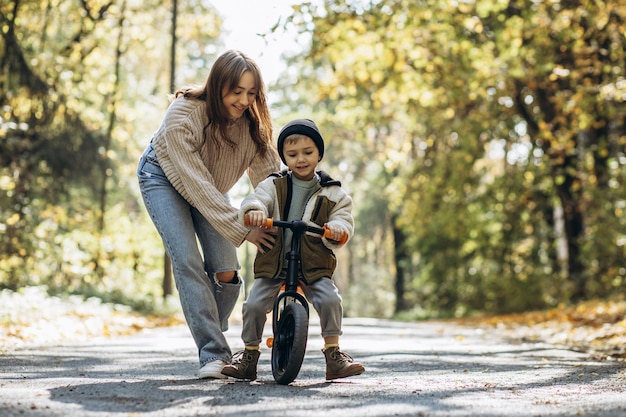 Мать с маленьким сыном учит кататься на велосипеде в парке