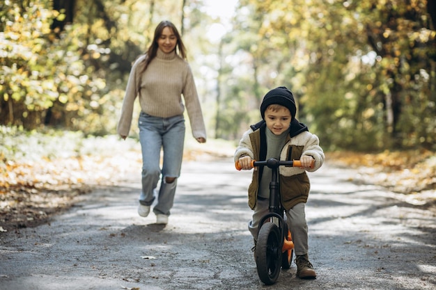 公園で自転車に乗ることを教える小さな息子を持つ母