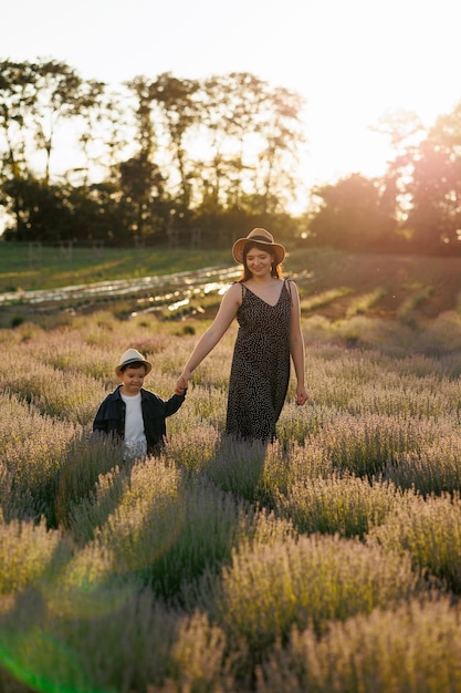 Mother with a little son walking in a lavender field at sunset