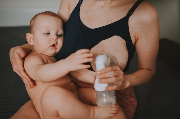 Фото Мать с новорожденным мальчиком держит его на руках, обнимая молокоотсос