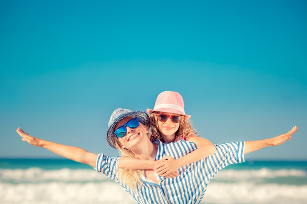 Mother with opened arms and her daughter hugging her at the beach