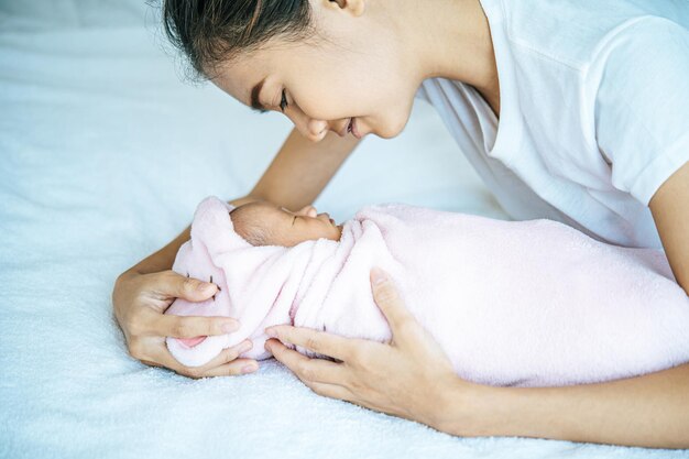 写真 家でベッドで寝ている赤ちゃんと一緒にいる母