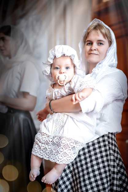 Foto una madre con un bambino piccolo in una chiesa cristiana ortodossa o tempio prega o è venuto al sacramento del battesimo o a un servizio credenti in un luogo santo all'altare o alle icone