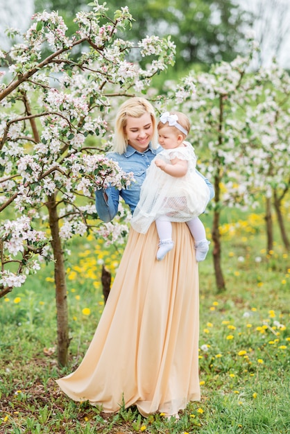 Mother with a small child on a walk in a blooming garden.