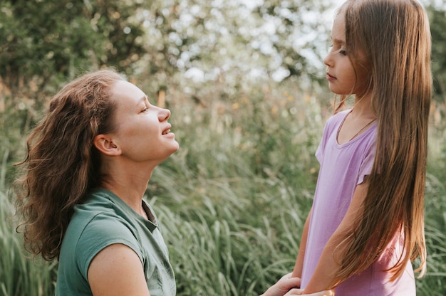 A mother with a small intra channel hearing aid communicates with her little daughter in nature outdoor