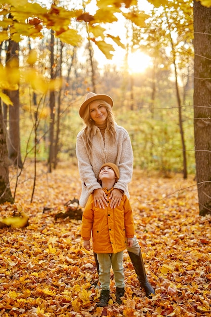 Mother with son in the autumn forest, portrait of family posing