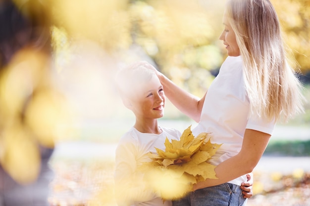 Mother with son have a rest in an beautiful autumn park at sunny day.